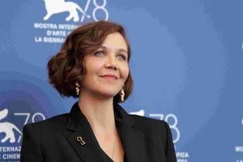 Woman with short brown hair in a black blazer, posing in front of a blue film festival backdrop.